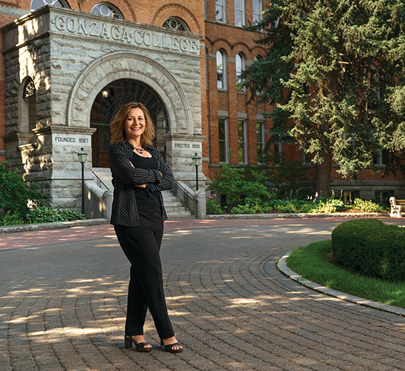 Мужчина в церемониальной одежде поднимает диплом с надписью «Gonzaga University»